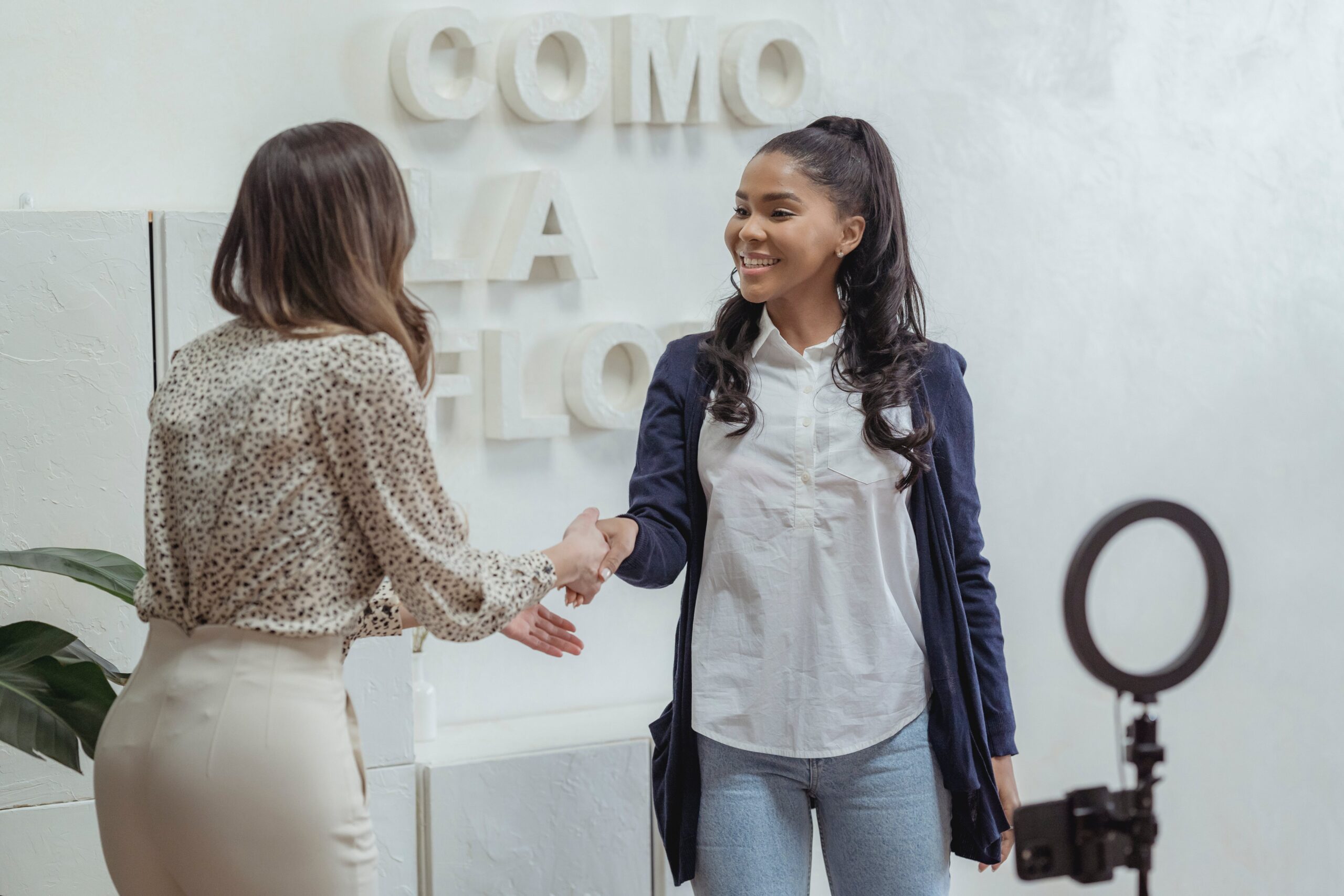 Two young career girls shaking hands and networking.
